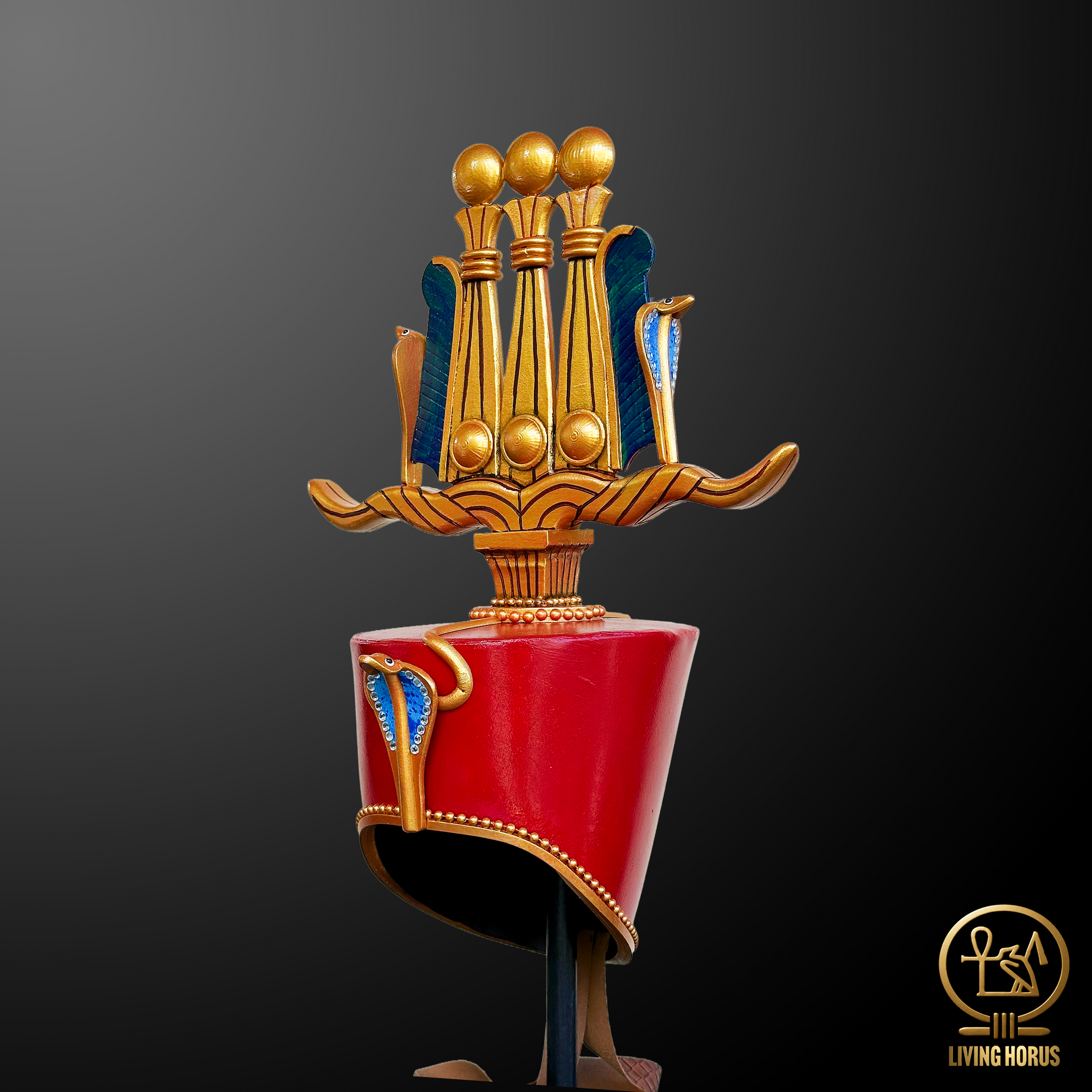 Decorative headpiece with red base and gold and blue accents on a dark background