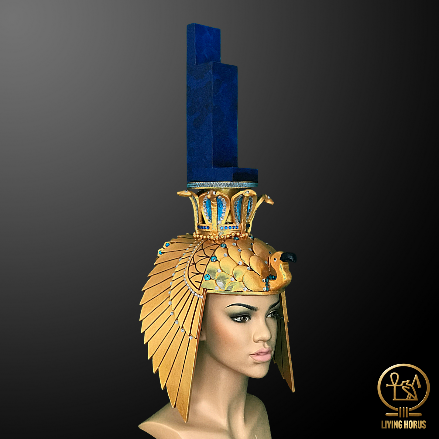 Mannequin head wearing an Egyptian-style headdress with blue and gold elements on a dark background.